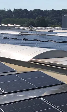 A huge PV installation on the roof of an industrial building, sunlight is reflected in the panels.