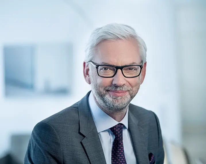 VERBUND CEO Michael Strugl wears a grey suit and tie. He has white hair, glasses and a grey beard. He smiles slightly.